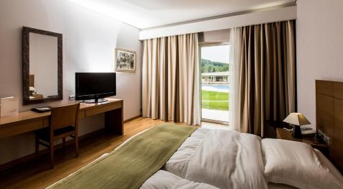 a hotel room with a bed and a desk and a window at Elpida Resort & Spa in Serres