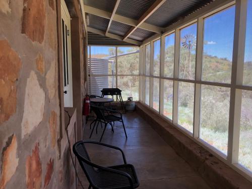 a screened in porch with chairs and tables and windows at Nudlamutana Hut - Vulkathunha-Gammon Ranges National Park in Arkaroola