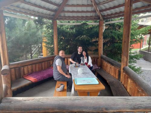 a group of people sitting at a table in a pavilion at Гостевой дом Коль-тор in Kegeti