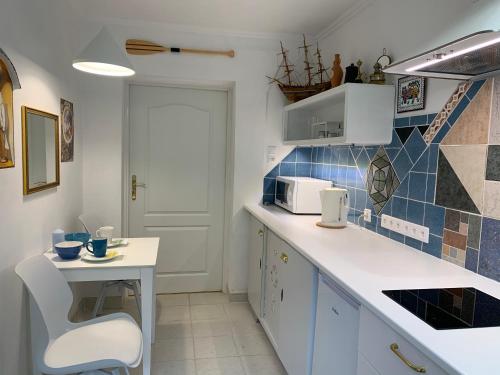 a kitchen with a white counter and a small table at Domek La Pergola in Łeba