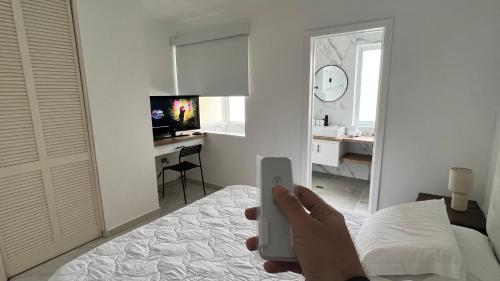 a person holding a wii remote in a bedroom at Cimarron Suites Playa Parguito in Aricagua