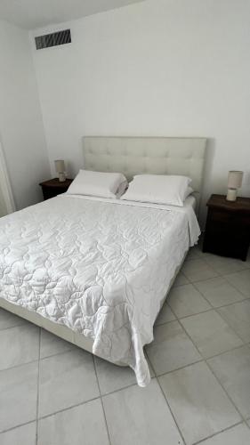 a white bed with white sheets and pillows on it at Cimarron Suites Playa Parguito in Aricagua