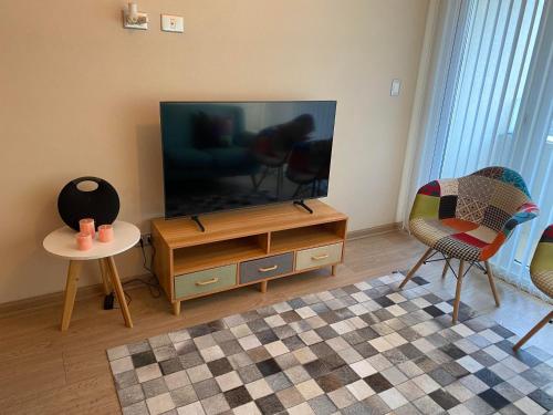 a living room with a flat screen tv and two chairs at Departamento Centro Chillan in Chillán