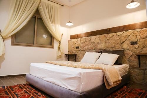 - une chambre avec un grand lit et un mur en pierre dans l'établissement Issli appartment, à Azrou