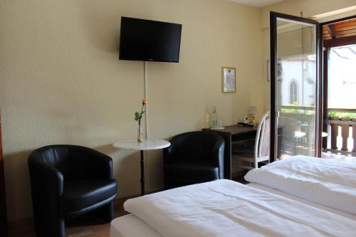 a hotel room with two chairs and a bed and a tv at Hotel Gasthof Rössle in Rottenburg