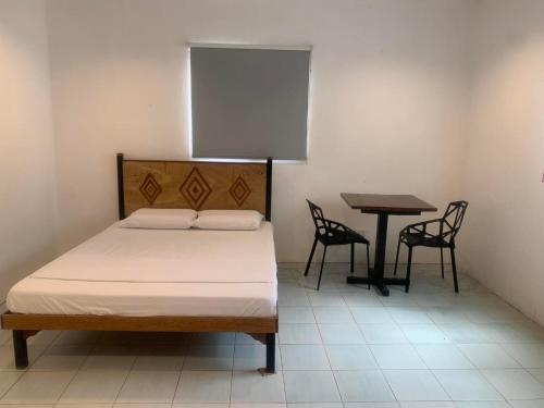 a bedroom with a bed and a table and chairs at Nacho Hostel Cebu in Bulacao