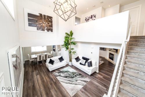 a living room with white furniture and a staircase at LUXURIOUS 6 Bed Home I Fireplace I near Sports Park I with Double Garage & Fast WiFi! in Edmonton