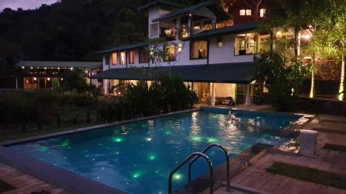 a swimming pool in front of a house at night at Sinharaja Forest Edge in Deniyaya