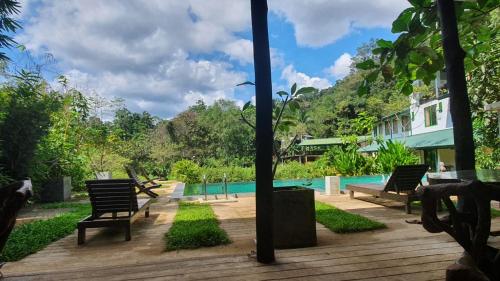 a wooden deck with benches next to a swimming pool at Sinharaja Forest Edge in Deniyaya