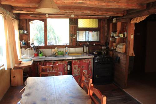 a kitchen with a table and a stove and a sink at La Casa del Viajero Hostel in El Bolsón