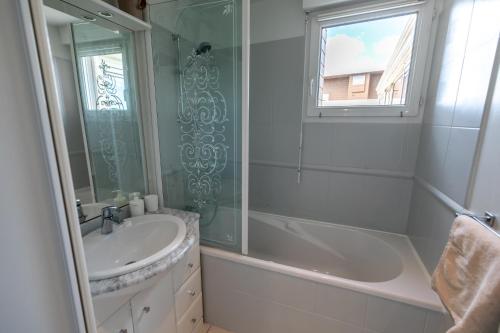 een badkamer met een bad, een wastafel en een douche bij L' Évéa Rooftop in Le Relecq-Kerhuon