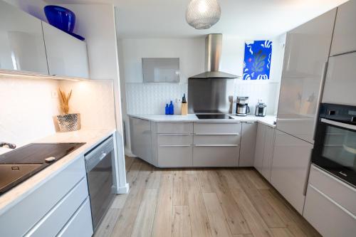 une cuisine avec des armoires blanches et un plancher en bois dans l'établissement L' Évéa Rooftop, à Le Relecq-Kerhuon