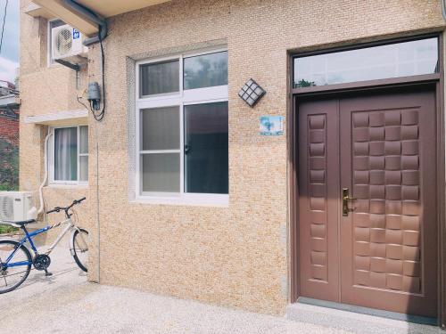 a bike parked next to a house with a brown door at 四季小空間 in Pingtung City