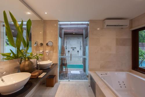 a bathroom with two sinks and a tub and a shower at Legian Beach Hotel in Legian