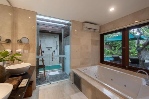 a bathroom with a tub and a sink and a shower at Legian Beach Hotel in Legian