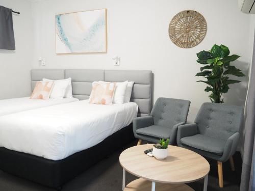 1 dormitorio con 1 cama, 2 sillas y mesa en The Esplanade Motel en Warners Bay