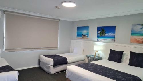 Habitación de hotel con 2 camas y ventana en Marco Polo Motor Inn Taree, en Taree