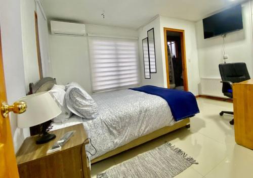 a bedroom with a bed and a desk with a lamp at Hostal Ejecutivo in Victoria