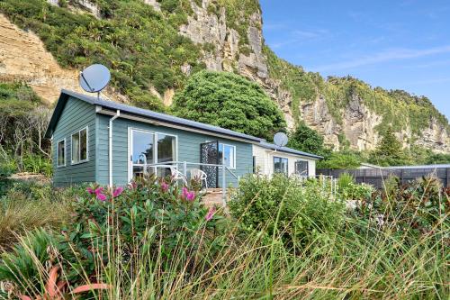 a green house in front of a mountain at Punakaiki Beachfront Motels in Punakaiki