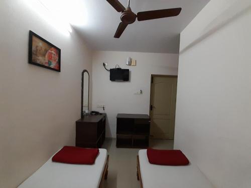 a room with two beds and a ceiling fan at SUPREME RESIDENCY in Coimbatore