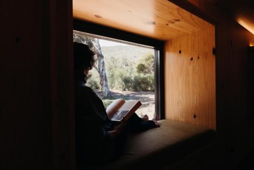 a person sitting in a window reading a book at Iron Creek Bay Estate in Sorell