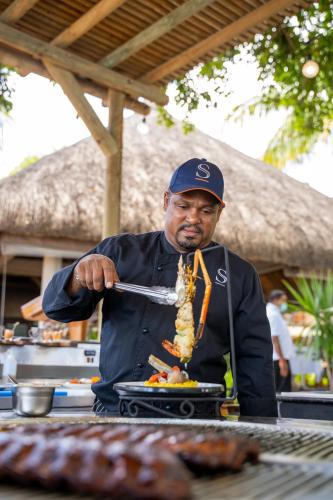 a man is preparing food on a table with meat at Sands Suites Resort & Spa in Flic-en-Flac