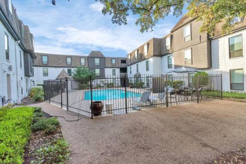 a fence with a pool in front of a building at Lovely 2 Bedroom + Den Apartment at Medical Center - Sleeps 8 in Houston