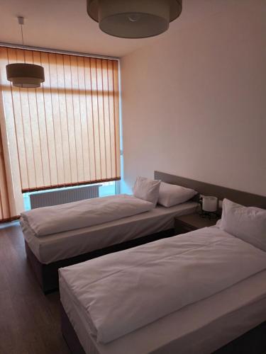two beds in a hotel room with a window at Parizs Garden Apartments in Debrecen