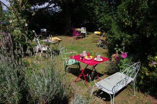 een rode tafel en stoelen in de tuin bij Maison d'Hôtes Lou Cliou in Cliousclat