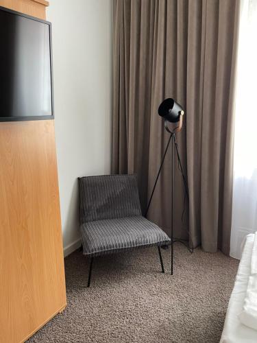 デュッセルドルフにあるMAX Hotel Düsseldorf Self-Check-inの椅子、ランプ、テレビが備わる客室です。