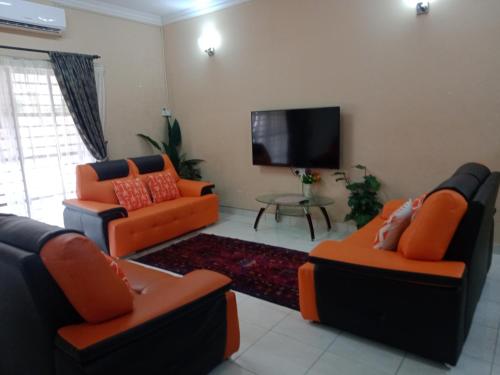 sala de estar con 2 sofás y TV de pantalla plana en Cosy P6 Homestay, en Puchong