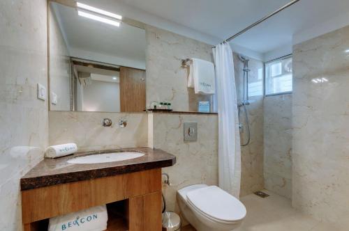 a bathroom with a sink and a toilet and a shower at The Beacon Hotel Vadodara in Vadodara