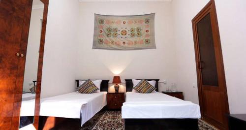 2 camas en una habitación con paredes blancas en Habibi Bukhara, en Bukhara