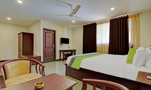 Una habitación de hotel con una cama, una mesa y sillas. en Treebo Prince, en Kottayam