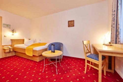 a hotel room with a bed and a table and chair at Alpenhotel Rieger in Mittenwald