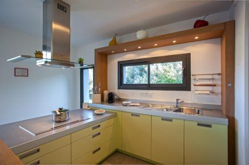 盧米奧的住宿－Villa U Spanu，厨房配有黄色橱柜、水槽和窗户。