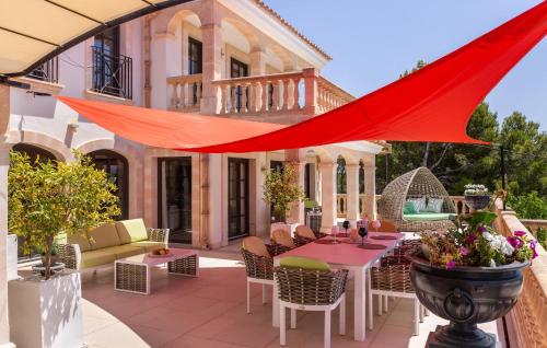 a patio with a red umbrella over a table and chairs at Villa Chef Cuisine in Costa d'en Blanes