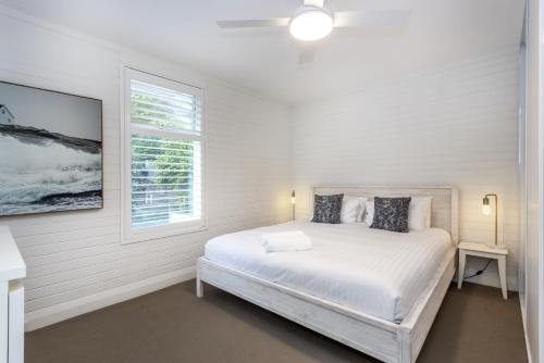 a white bedroom with a bed and a window at Cottesloe Beach View Apartment - EXECUTIVE ESCAPES in Perth