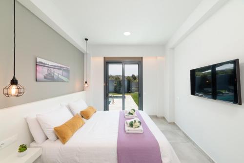a white bedroom with a bed and a tv at Villa Zaneti by PosarelliVillas in Agia Marina Nea Kydonias