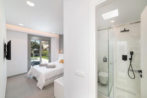 a white bedroom with a bed and a shower at Villa Ampela by PosarelliVillas in Agia Marina Nea Kydonias