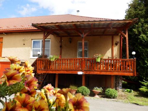 a house with a wooden deck with flowers in front at Guesthouse Ilona in Veľký Kamenec