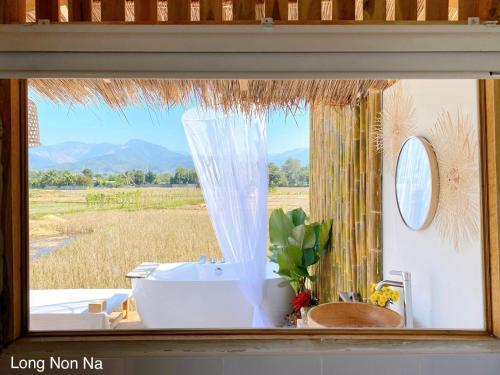 a bathroom with a tub and a window with a view at ลองนอนนา Long Non Na in Ban Lao
