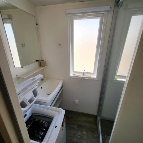 une salle de bain blanche avec un lavabo et une fenêtre dans l'établissement La Pointe de Sel, à Canet