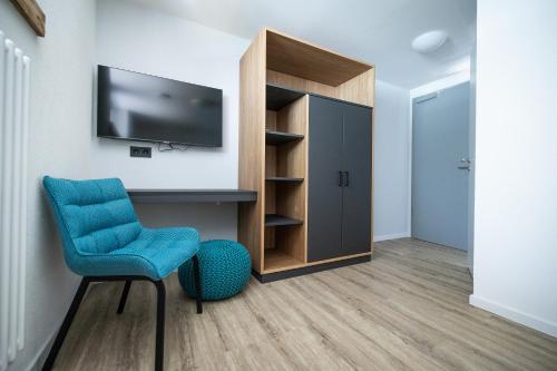 a room with a tv and a chair and a cabinet at Rübli in Freiberg am Neckar