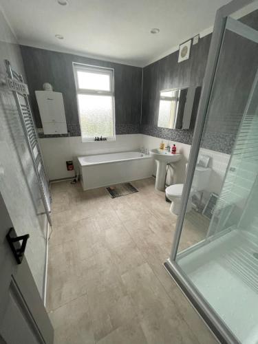 a bathroom with a tub and a toilet and a sink at Bentley Place in Crewe
