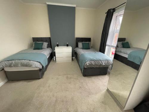 a bedroom with two beds and a mirror at Bentley Place in Crewe