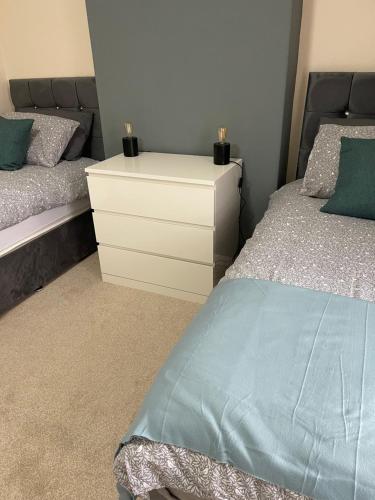 a bedroom with two beds and a white dresser at Bentley Place in Crewe