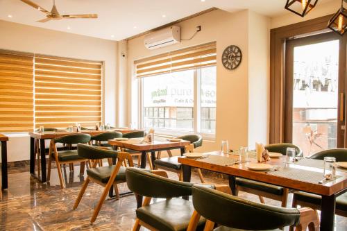 a restaurant with wooden tables and green chairs at Hotel Dream Inn in Rishīkesh
