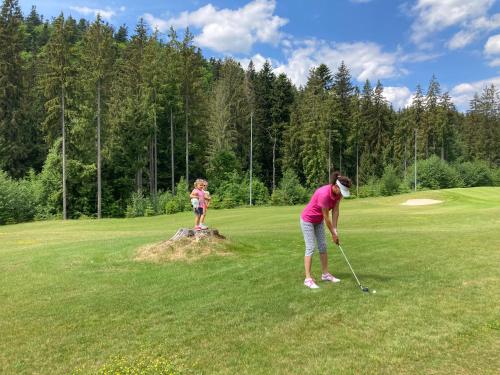 a woman and a child playing golf on a golf course at Chata pri jaskyni Bystrá in Bystrá