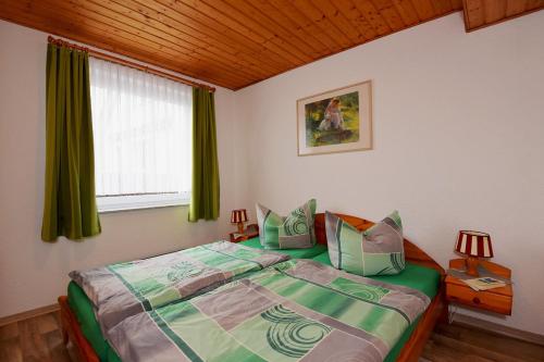 a bedroom with a bed with green sheets and a window at Ferienwohnungen Stützel in Oberellen